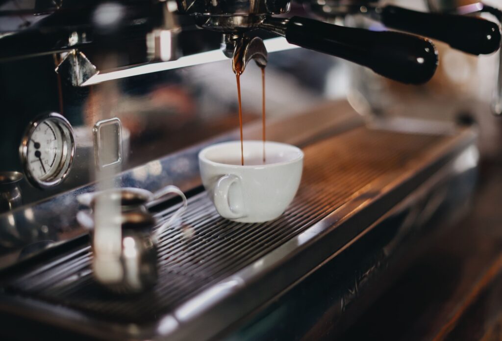 Zoom em cafeteira profissional preparando café em cafeteria.