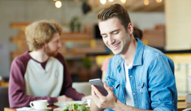 Homem em restaurante acessando cardápio digital diretamente pelo celular.