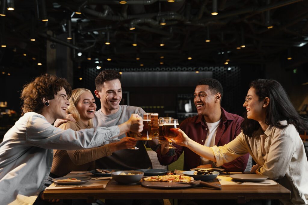 5 indivíduos em bar brindando com cerveja.