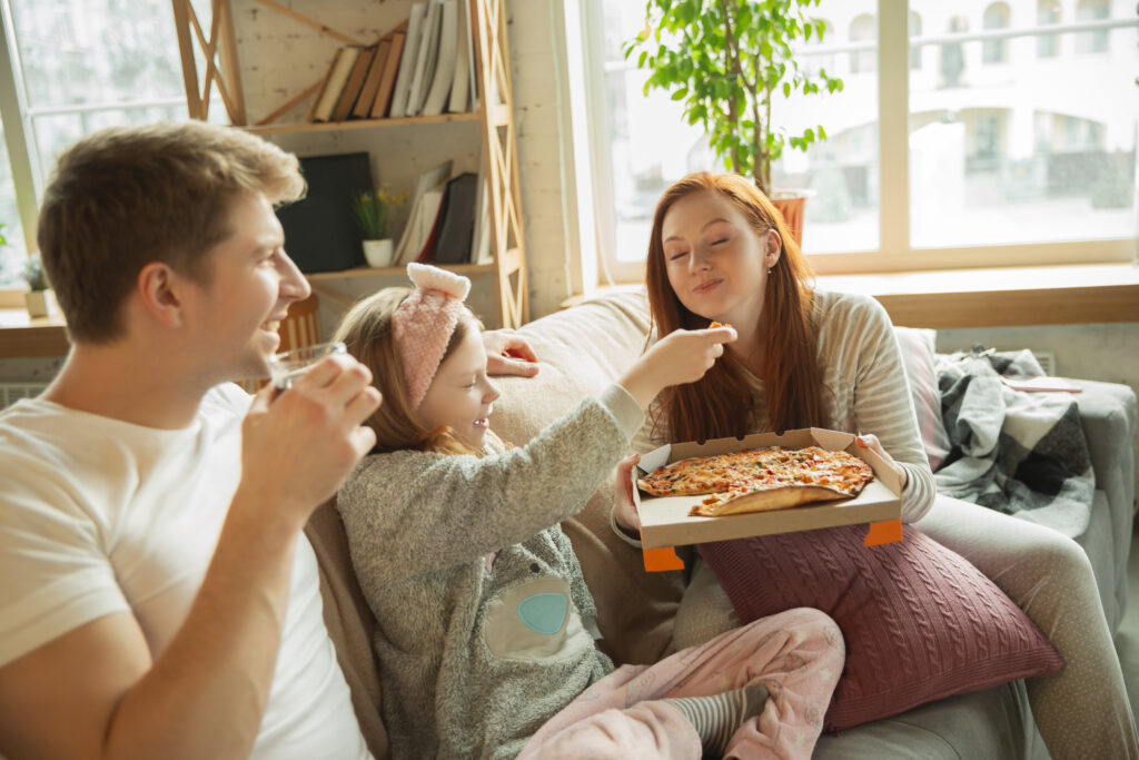 Família comendo pizza delivery em casa.