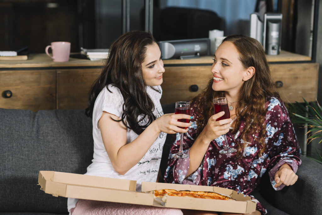 casal de mulheres comendo pizza delivery em casa
