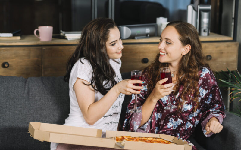 casal de mulheres comendo pizza delivery em casa