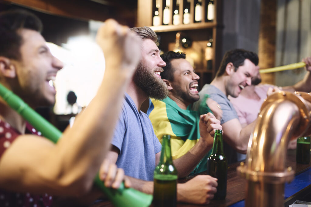 Amigos em balcão de bar comemorando ao assistir jogo