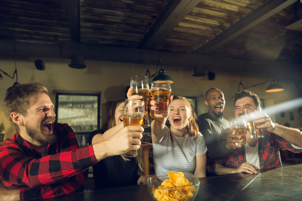 Amigos em balcão de bar comemorando ao assistir jogo