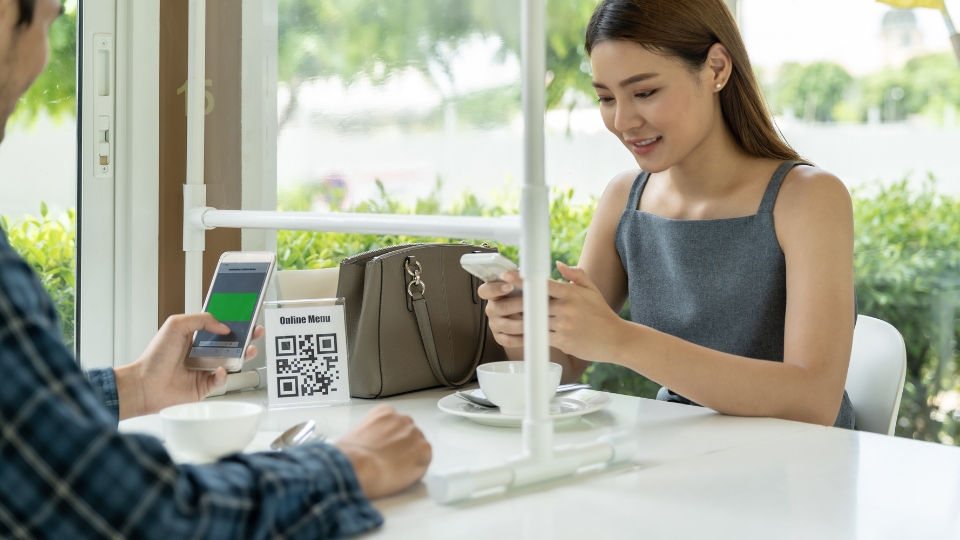 Celular lendo QR Code de menu em mesa de restaurante