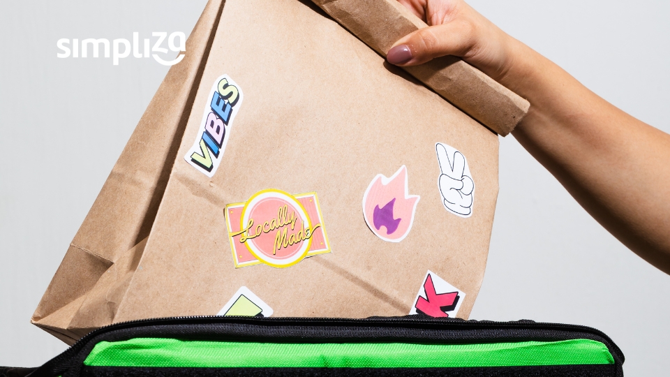 zoom em mão segurando uma embalagem de comida com várias figurinhas coloridas coladas no pacote