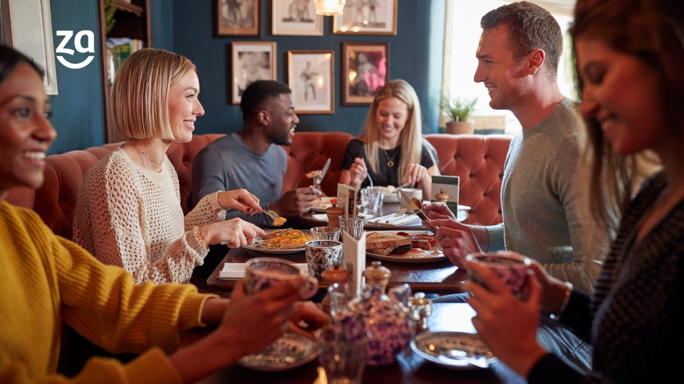 Mesa com pessoas felizes comendo em restaurante.