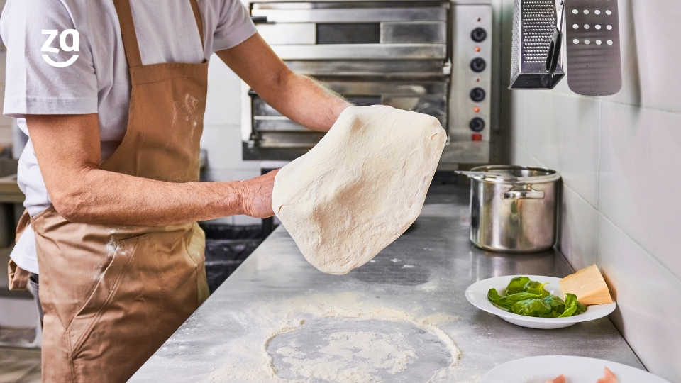 Zoom nas mãos de um chef preparando massa de pizza