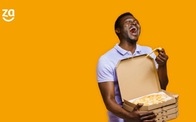 fundo amarelo; homem com caixas de pizza, a de cima aberta e ele puxando uma fatia enquanto sorri