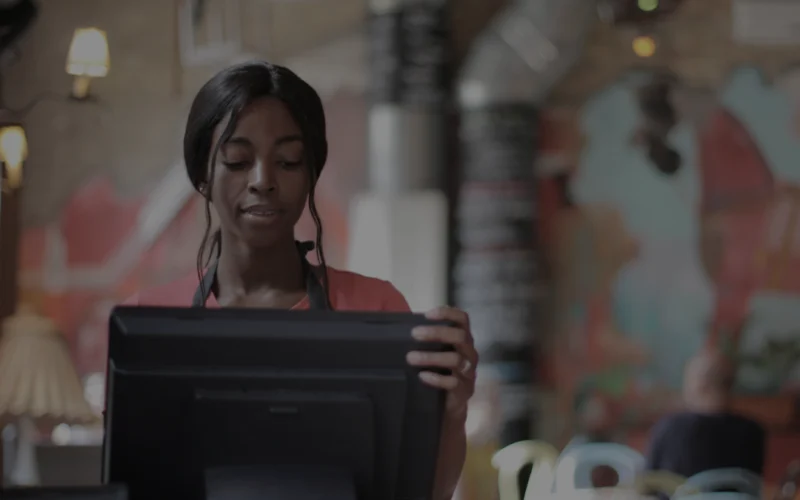 Uma mulher em um restaurante mexendo em um computador.