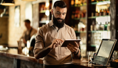 Homem mexendo em um tablet, dentro de um restaurante