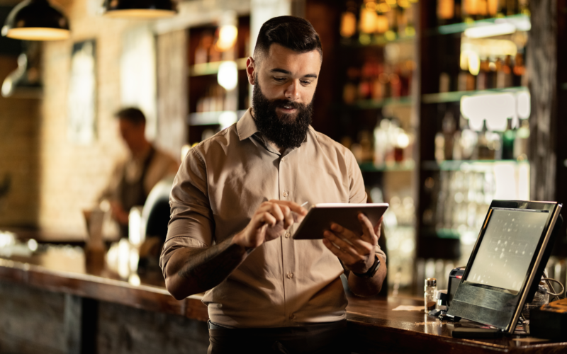 Homem mexendo em um tablet, dentro de um restaurante