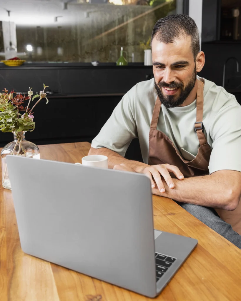 um homem em um restaurante olhando e sorrindo para um notebook