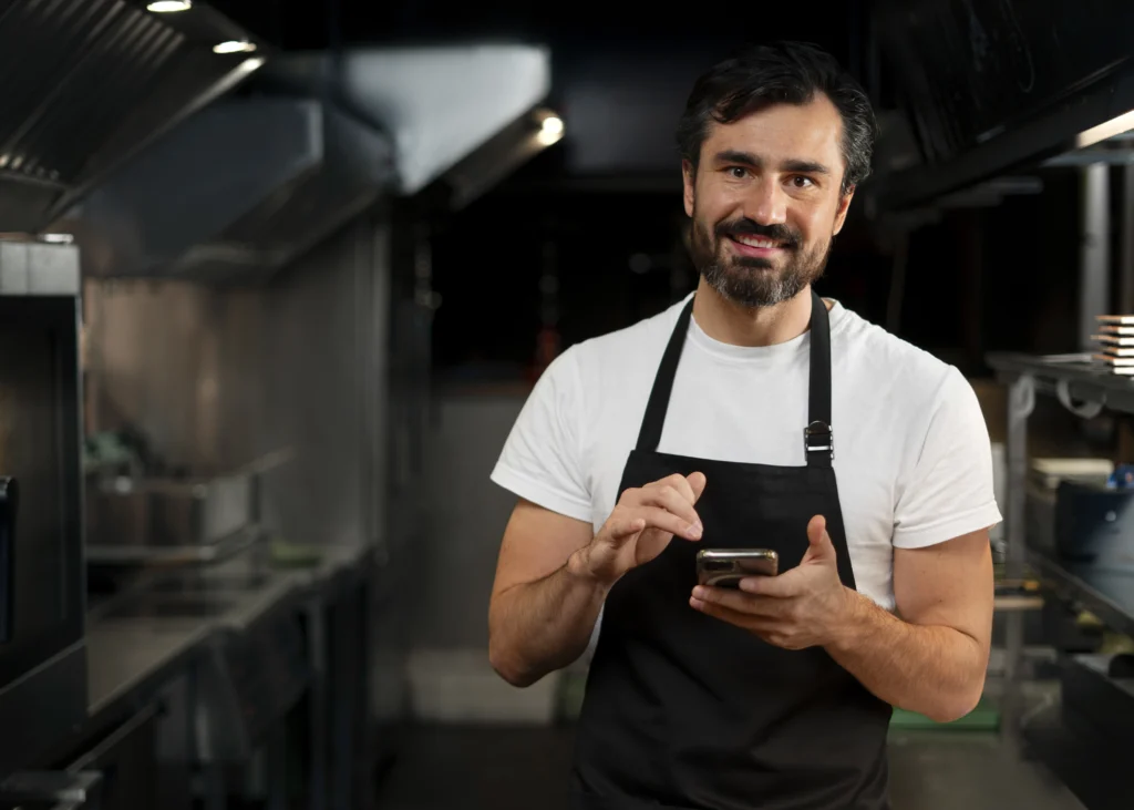 garçom na cozinha utilizando o celular