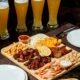 copus de cerveja e tabua de comida em uma mesa